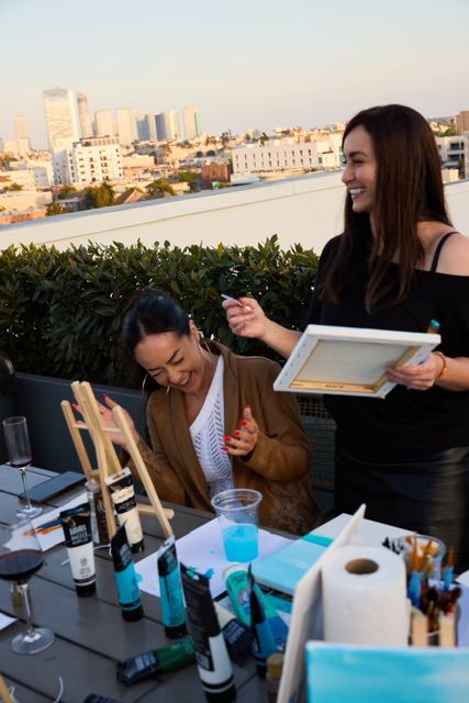 Zuzi guiding a guest one on one during a painting class with the Los Angeles skyline in the background